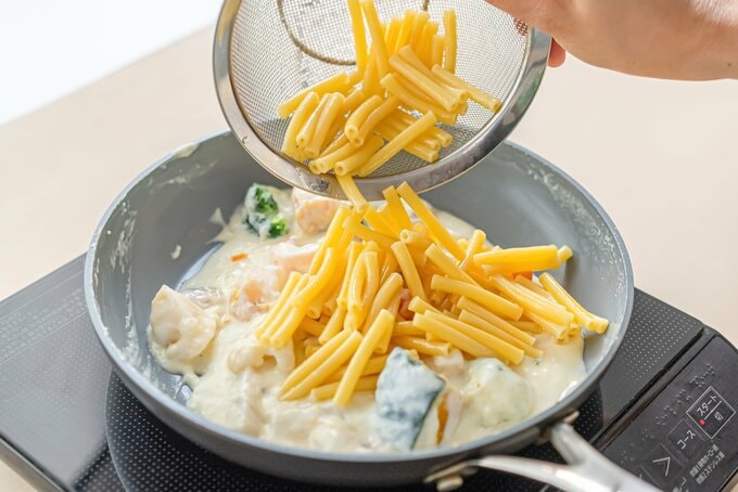 マカロニをフライパンにくわえる