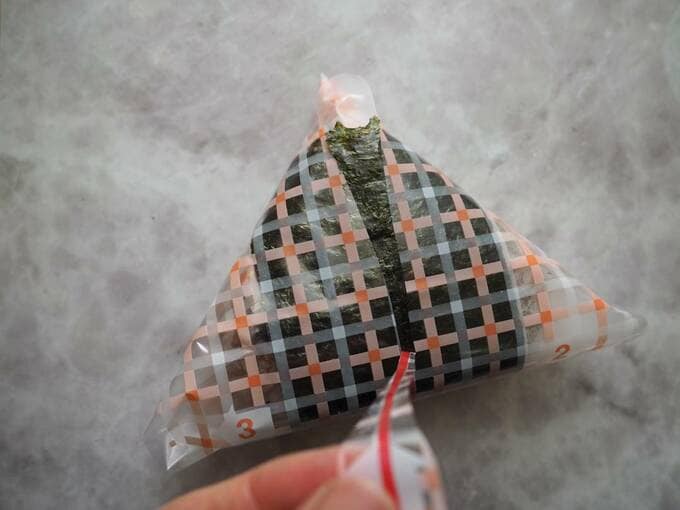 三角形おにぎりのフィルムをはがす様子