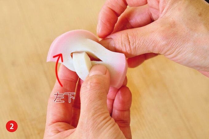 かまぼこの左下を中央の切れ目に差し込む様子