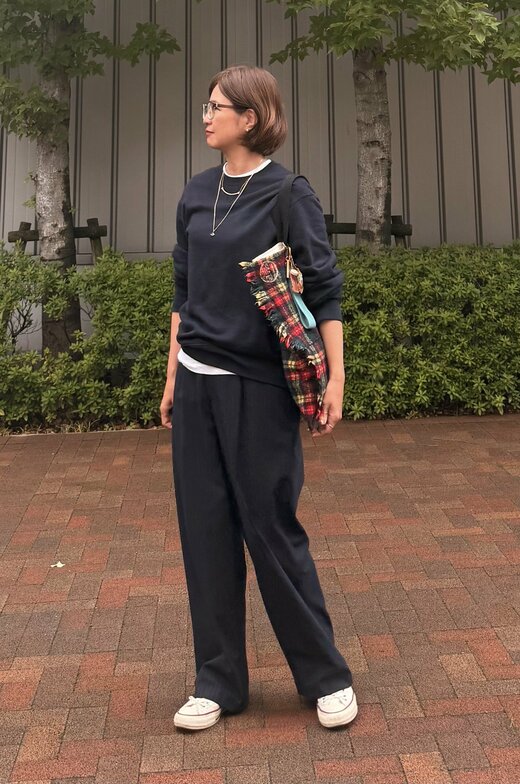 上下の衣服が黒、チェックのトートバッグをもっている