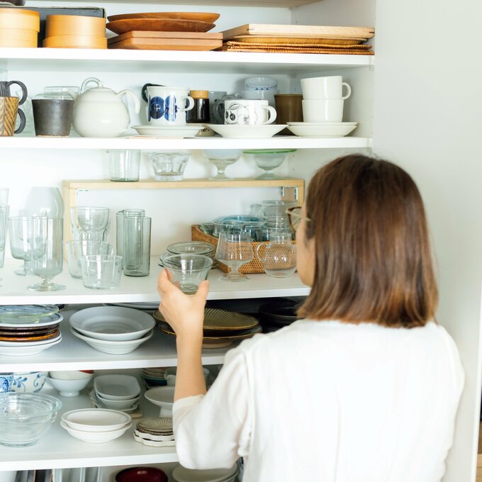 食器棚に食器をしまう女性