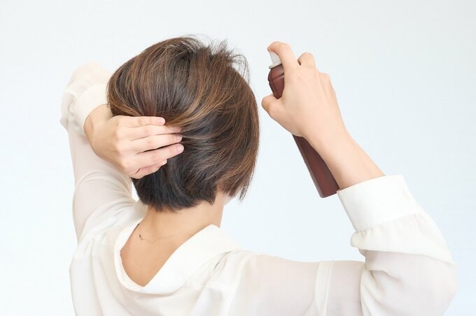 ヘアスプレーをかける女性
