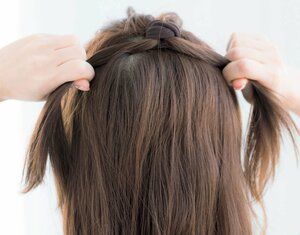 女性両手で髪を両サイドにひっぱる