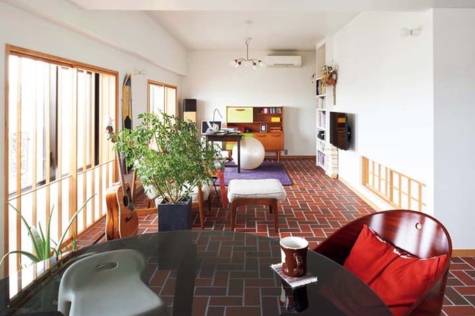 床をレンガタイルで仕上げた、北欧デザインの家具が並ぶリビングダイニング