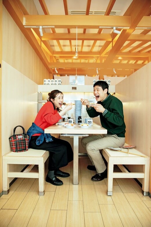 回転すし店ですしを食べようとしている笑顔の男女