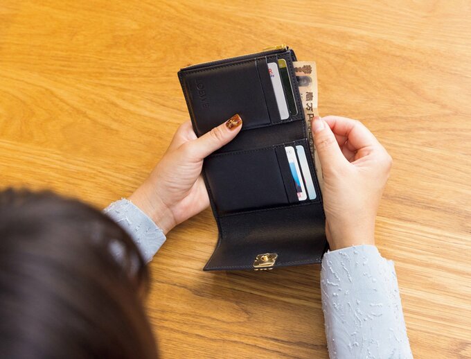 黒の財布にお札とクレジットカードが入った様子