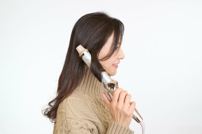 ヘアアイロンを使用する女性