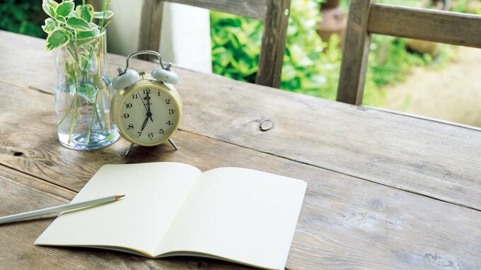 机に置かれた目覚まし時計とノート
