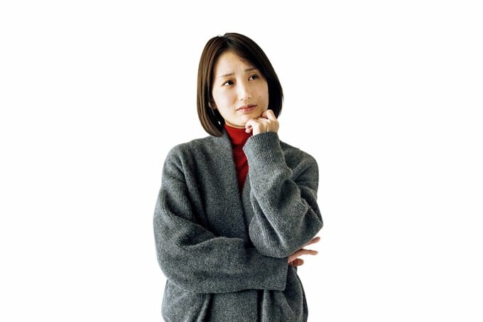 立ったまま考えるポーズをしているボブヘアの女性