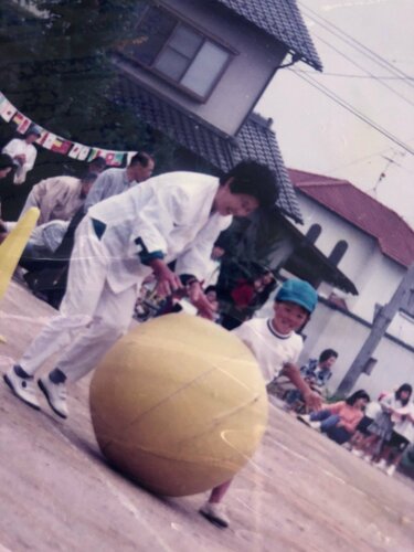 運動会で玉転がしをする女性と子ども