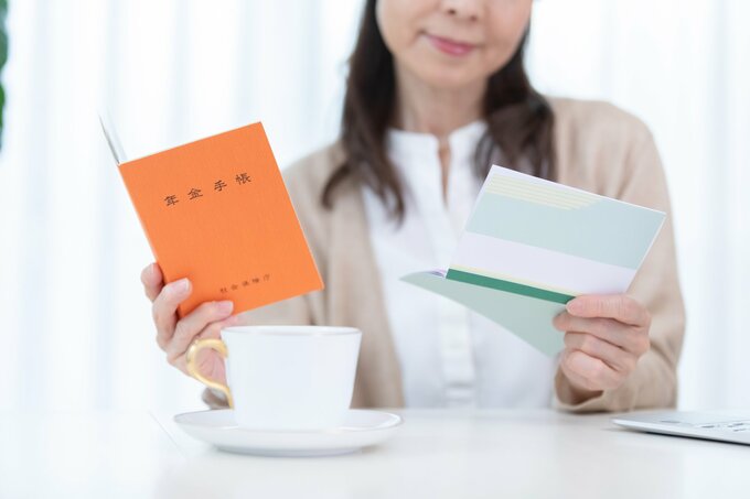 通帳、年金手帳をみて悩む女性
