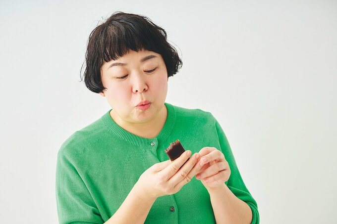 グリーンのカーディガンを着た女性が桜のようかんを食べる様子