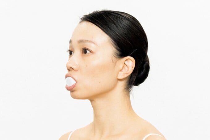 ペットボトルキャップをくわえ横を向く女性