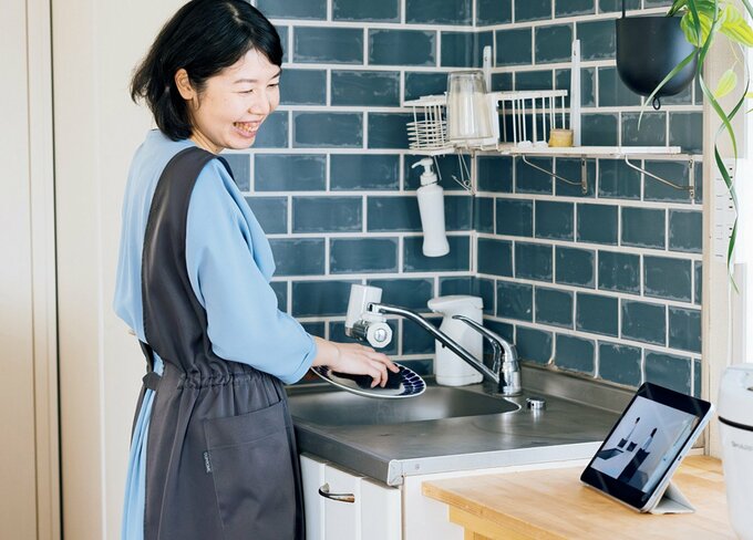 タブレットを見ながらキッチンでほほ笑む女性