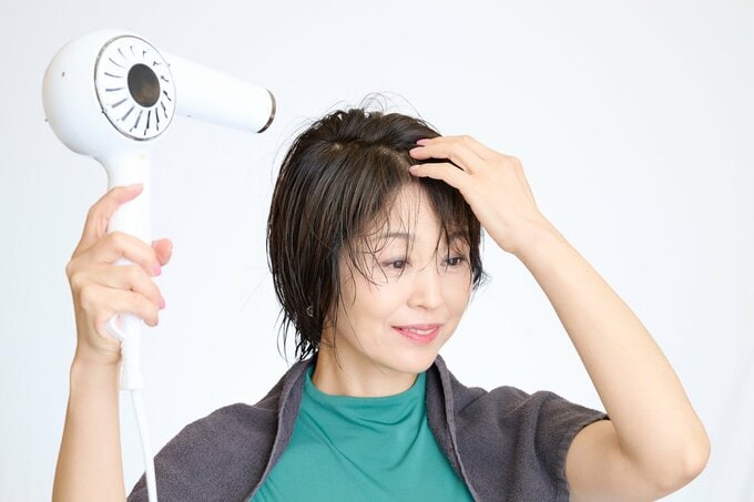 涼しい顔で髪を乾かす女性