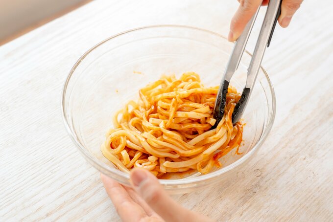 うどんに調味料を入れて混ぜる