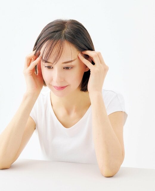 こめかみの辺りを指で押し上げる女性