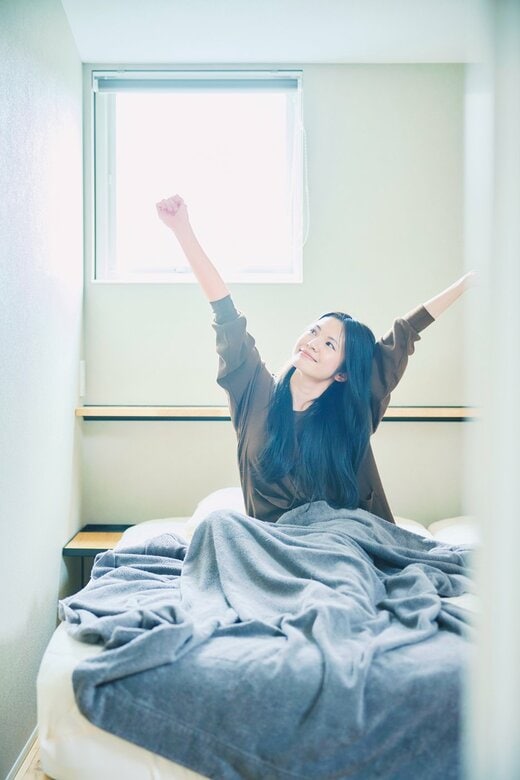 ベッドで伸びをする女性
