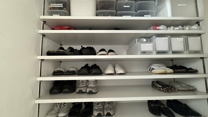 大きなシューズクローゼットの前に女性の後ろ姿が写っている。シューズクローゼットにはたくさんの靴が入っている。