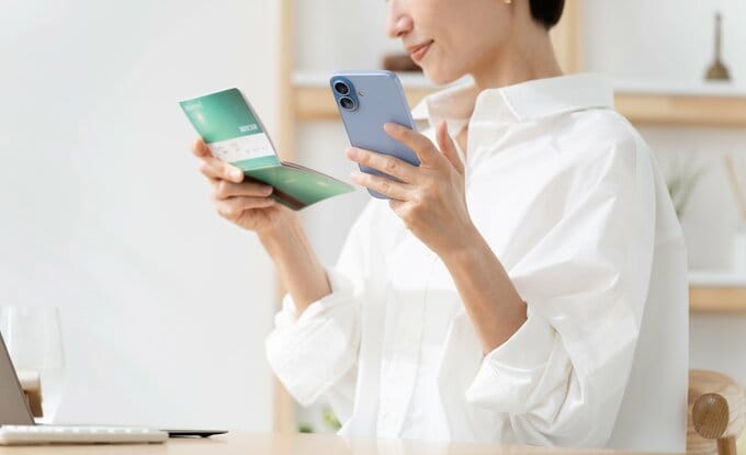 スマホと預金通帳を眺める女性