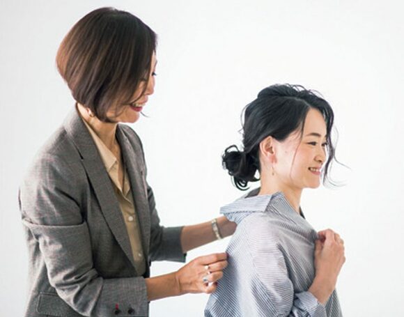 女性二人シャツの襟足をさわる