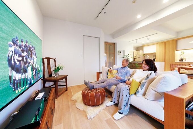 大きなテレビを置いたリビングでくつろぐ夫妻