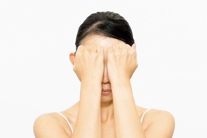 眉頭の上にこぶしを当てる女性