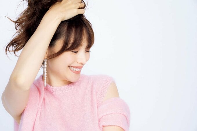 髪を上げて笑う女性