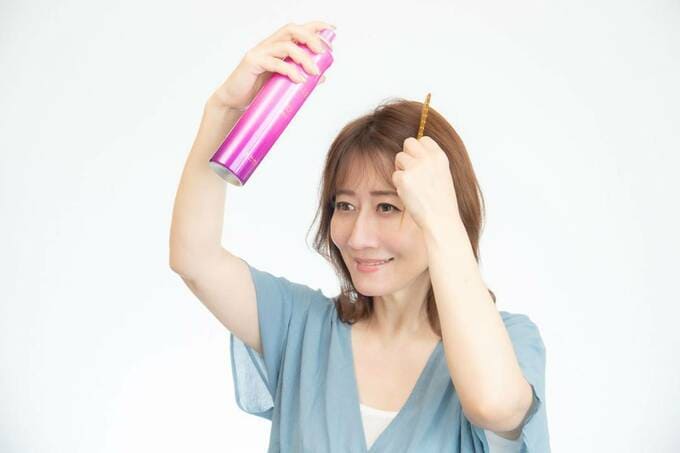 コームでアホ毛を押さえながら、スプレーをかける