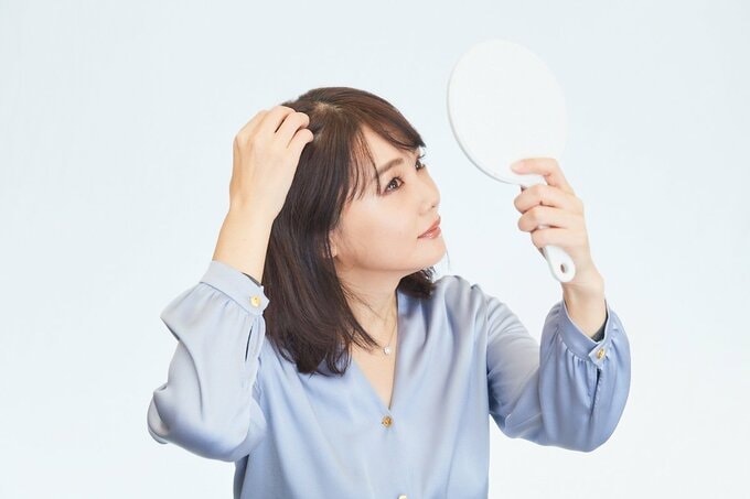 自分の頭皮を見ている女性
