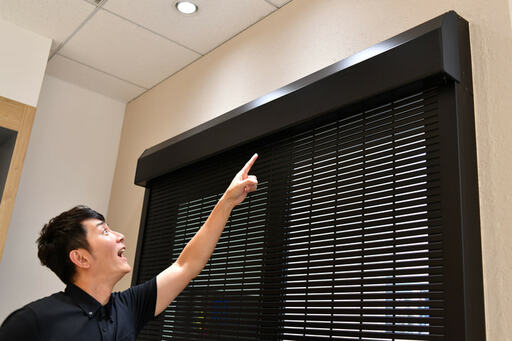 シャッター上部を指差す男性