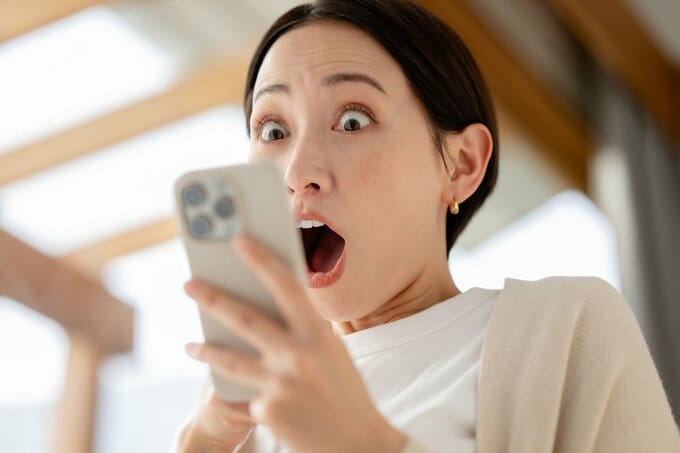 スマホを見て驚く女性