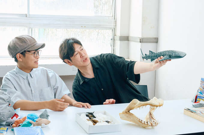 木彫りのジンベエザメを見るふたり