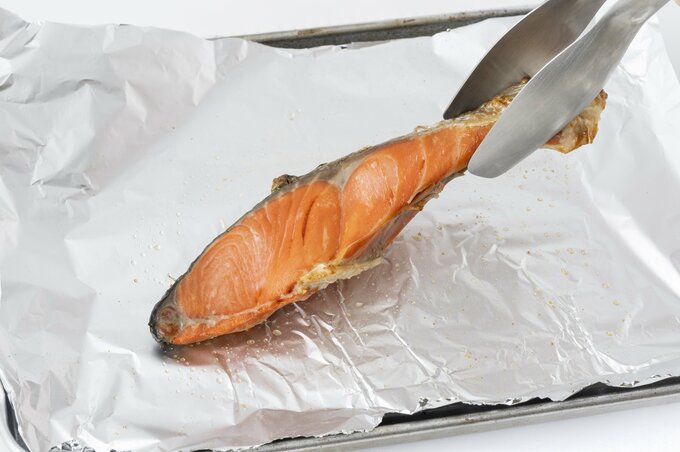 焼いた鮭をアルミホイルからはがしている図