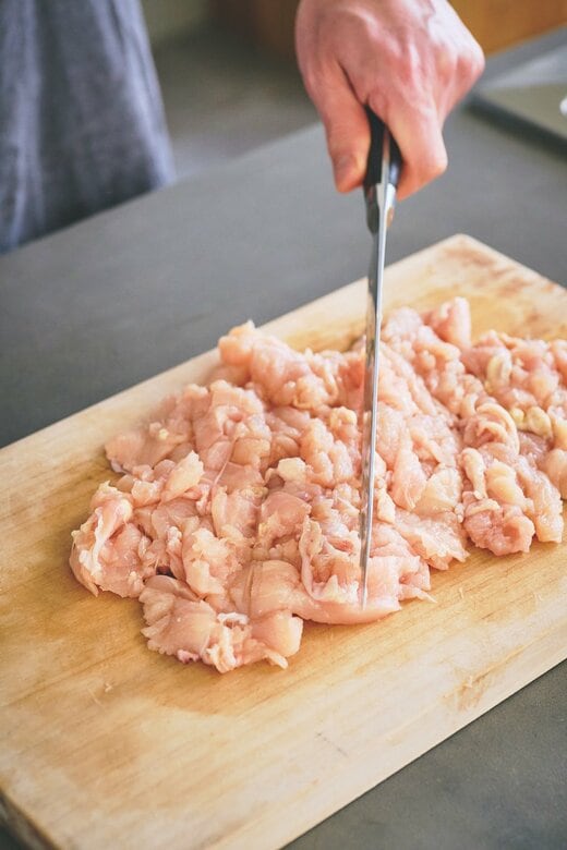 肉をまとめて包丁でたたく様子