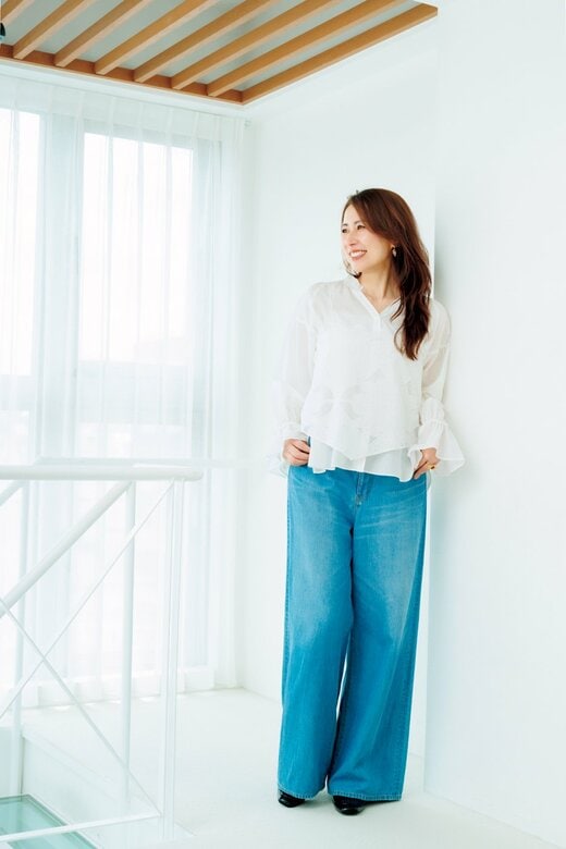 白のブラウスにジーンズを組み合わせたスタイルの女性