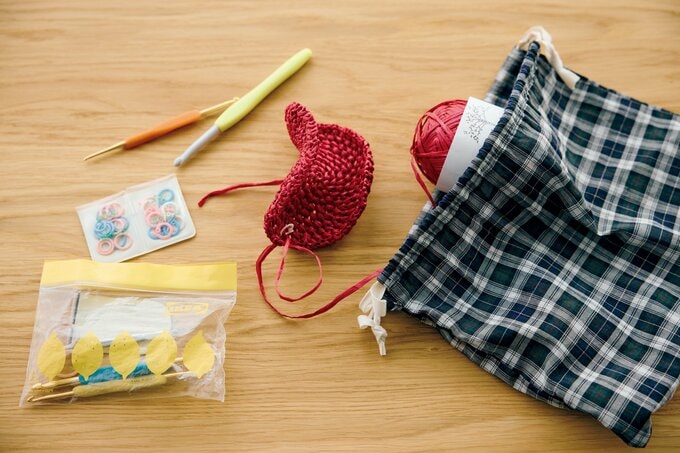 巾着から取り出した赤い毛糸や編み針とビニールの保存袋
