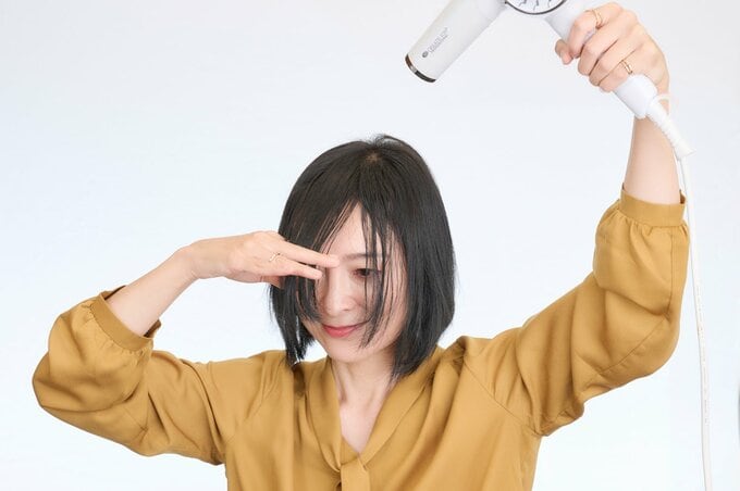 前髪に風を当てる女性