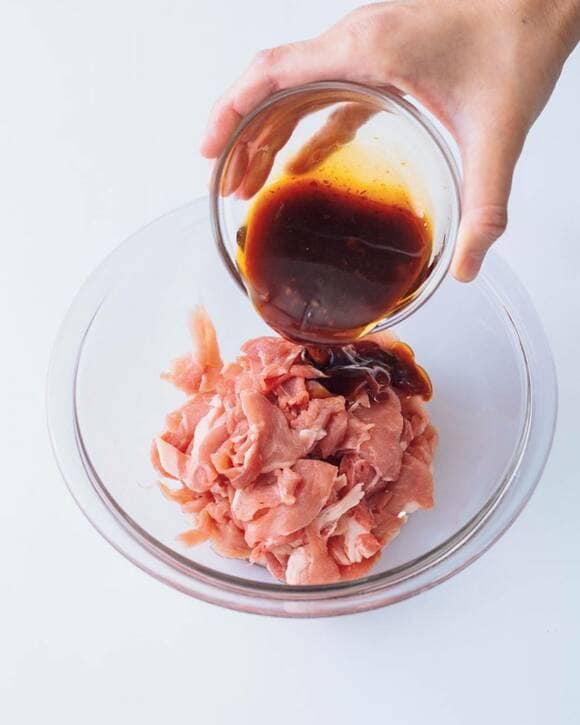 お肉が入ったボウルに調味料を加える様子