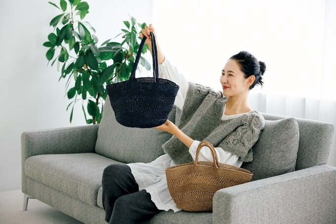 黒い糸で編まれたハンドバッグを眺めて微笑む女性