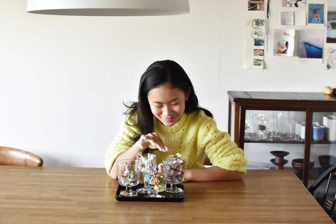 黄色の服を着た女性がグラスに入ったお菓子をとる様子