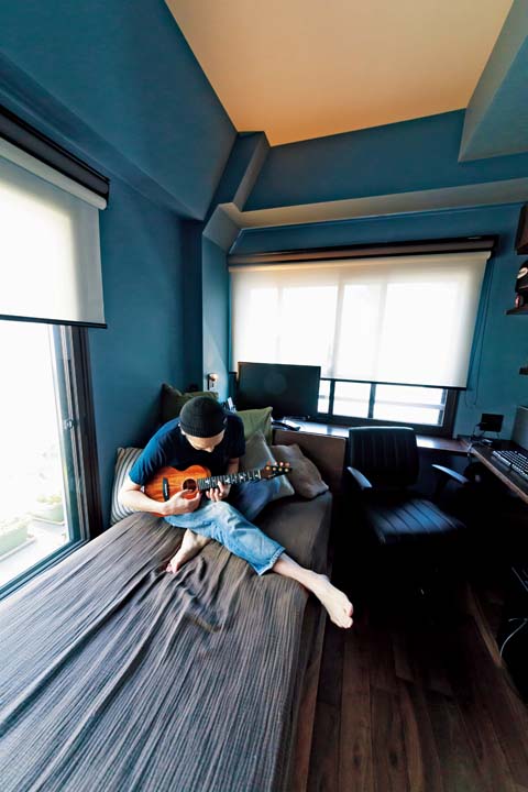 部屋でギターを弾く夫