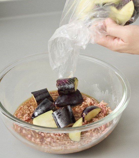 ひき肉と片栗粉、Aの材料を入れた耐熱ボウルにナスを加えた図