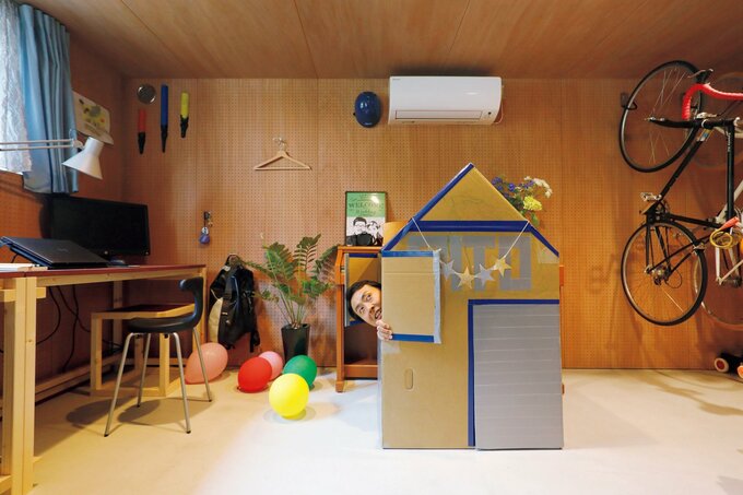 段ボールハウスから顔を出す田中さん