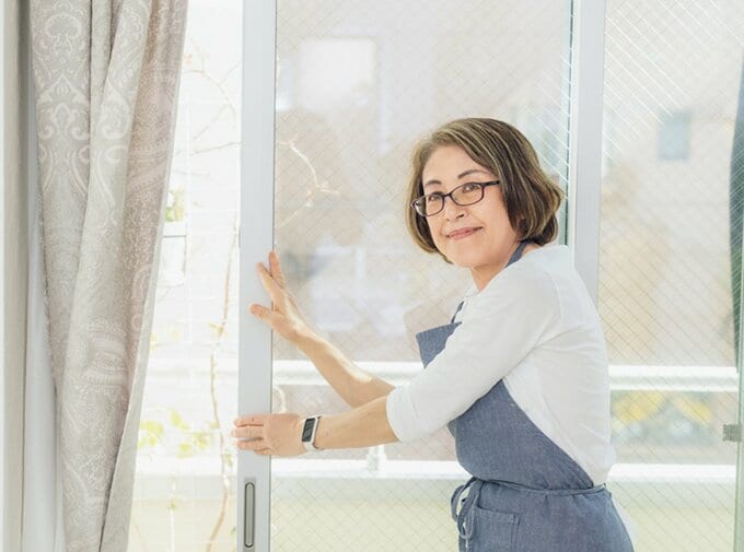 窓に手を添えて笑顔を見せる女性