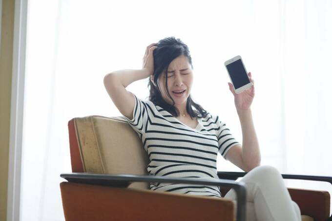 スマホを持って頭を抱える様子