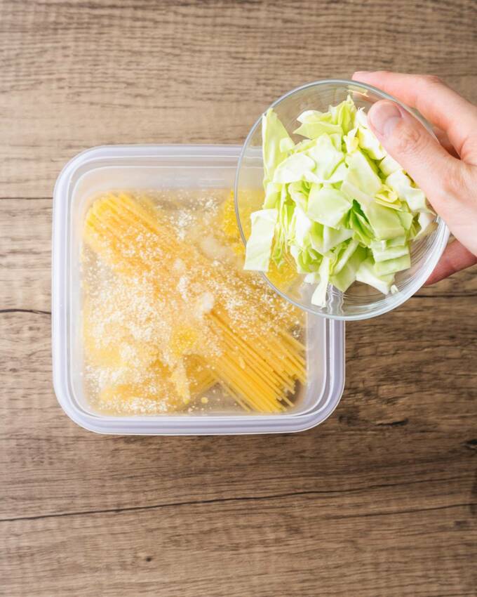 乾麺が入ったコンテナに野菜を入れる様子