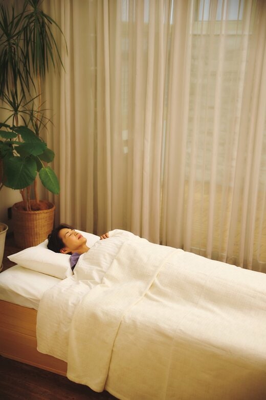 寝室で女性が白い布団に横たわって眠っている様子