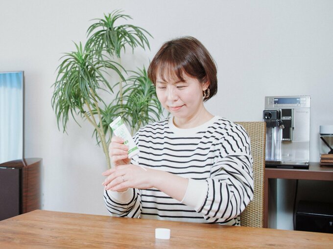 ダイニングテーブルでハンドクリームを塗る本間さん