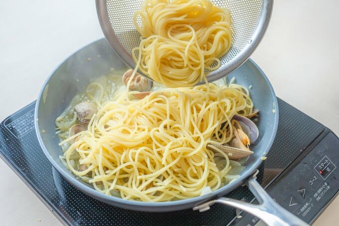 フライパンにスパゲティを加えている